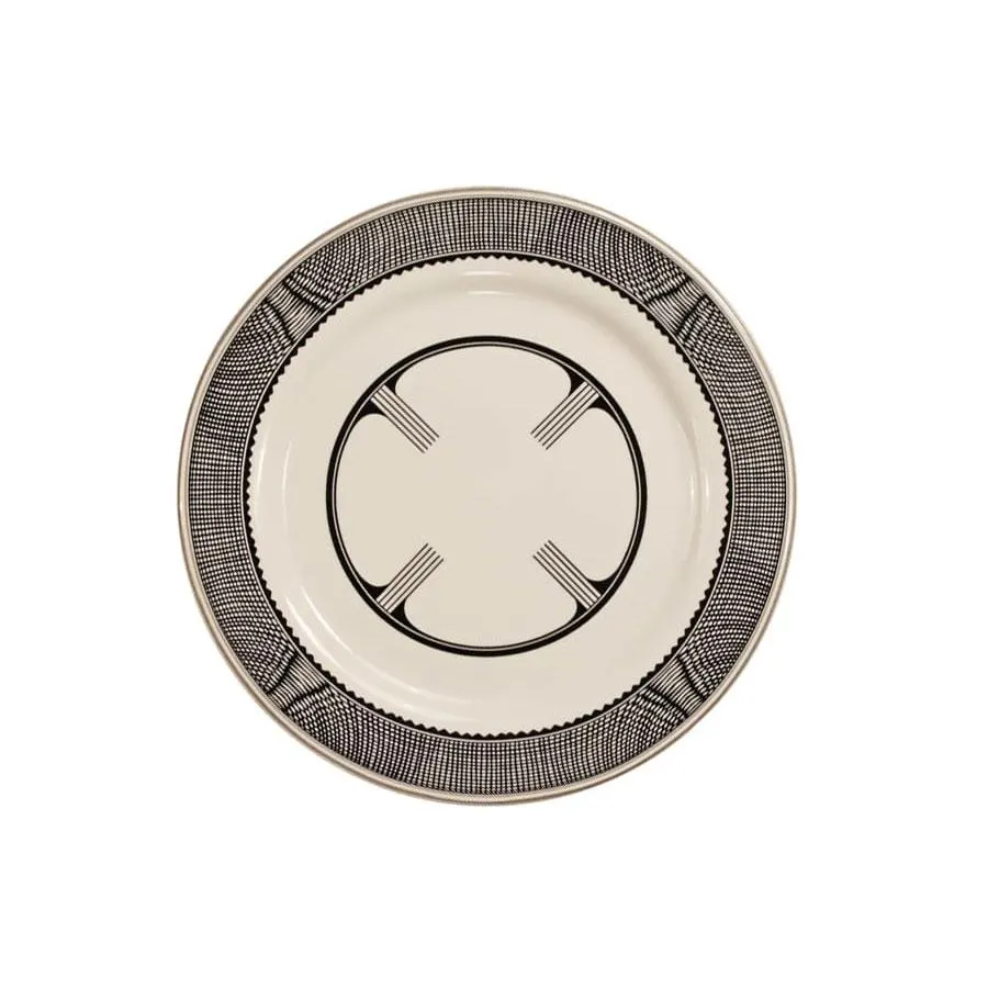 A round cream ceramic dinner plate with a black Art Deco geometric border pattern and a circular emblem at center, on a white background.