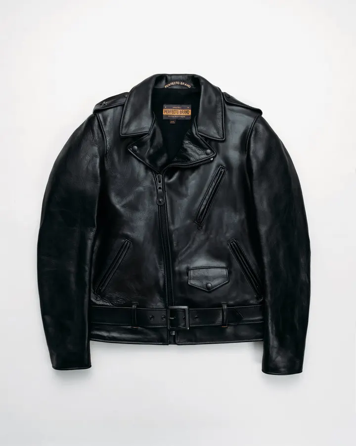 A black leather motorcycle jacket with an asymmetric zip front and belt, a 'Perfecto Brand' label at the collar, laid flat against a white background.