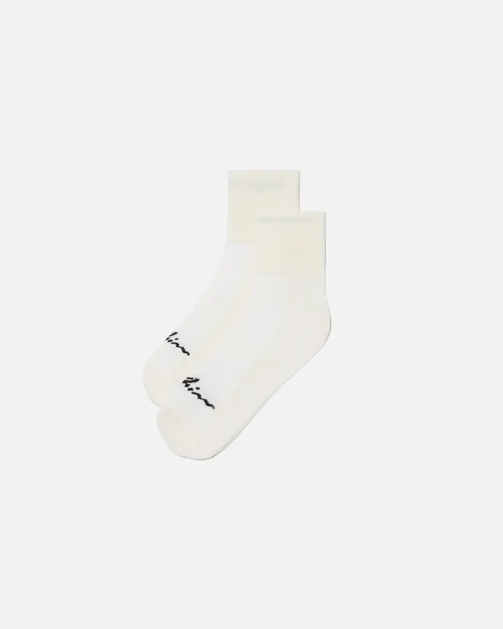 A single cream-colored ankle sock with a small woven WHIM wordmark near the toe, laid flat against a plain white background.
