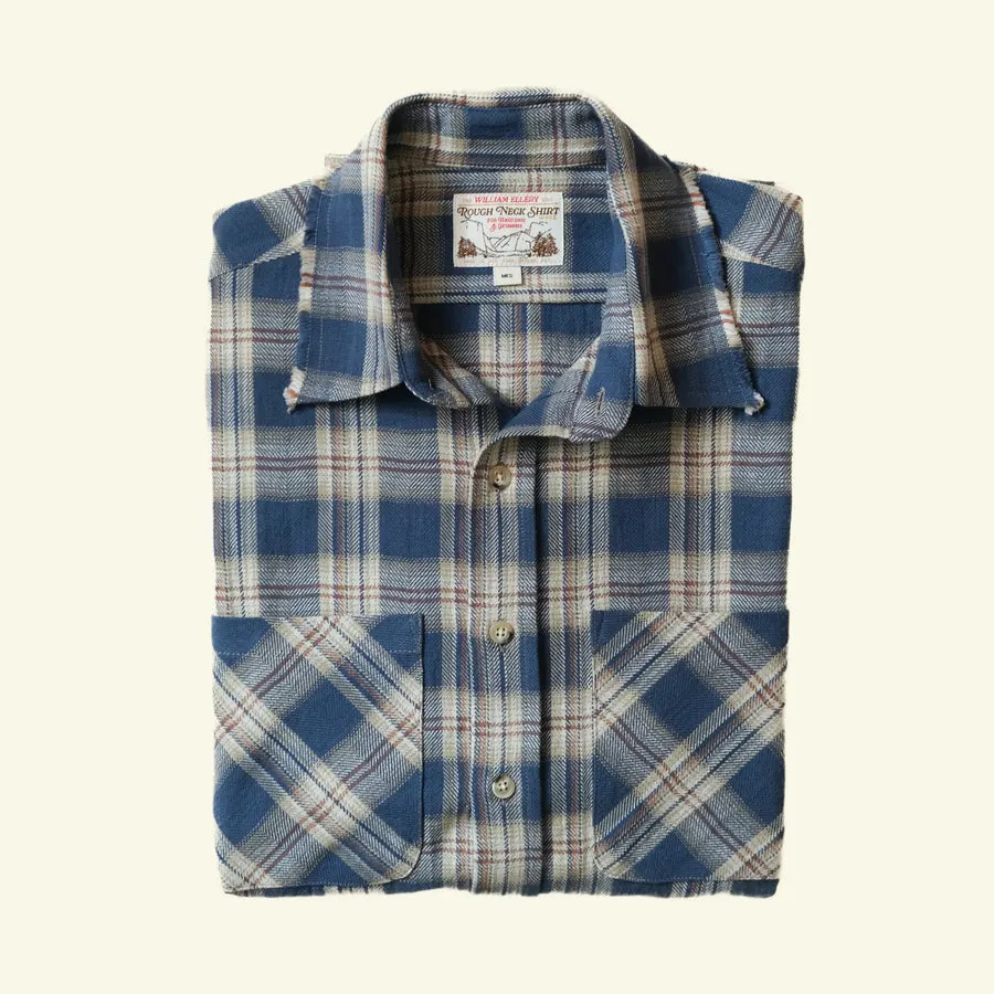 A blue-and-cream plaid flannel button-up shirt with two chest pockets, folded flat against a cream background.